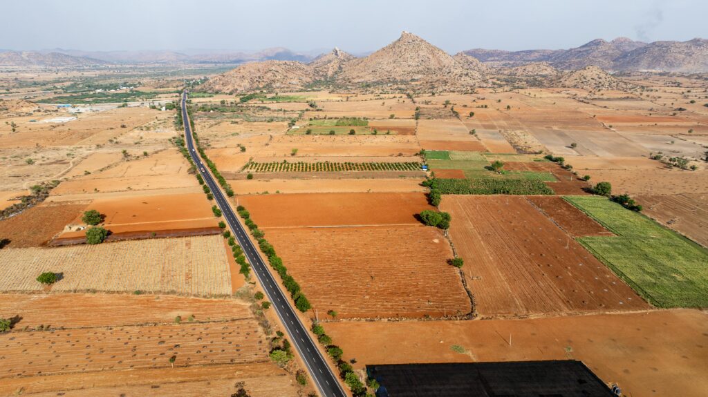 Aerial perspective of agricultural fields and a road intersecting the farmland landscape.